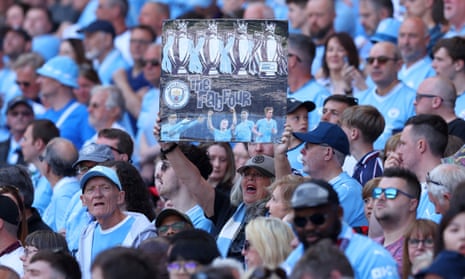 A Manchester City supporter holds a placard that celebrates the Manchester City team that won the fourth Premier League Title in a row.