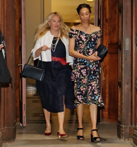 Two women walk through doorway.