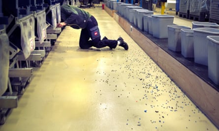 Lego’s production plant with a man kneeling, his head out of the picture in the machinery and a scattering a Lego pieces in the foreground