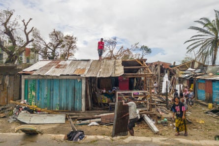 A man stands on top of the roof of a building in Toamasina after being hit by Tropical Cyclone Gezani