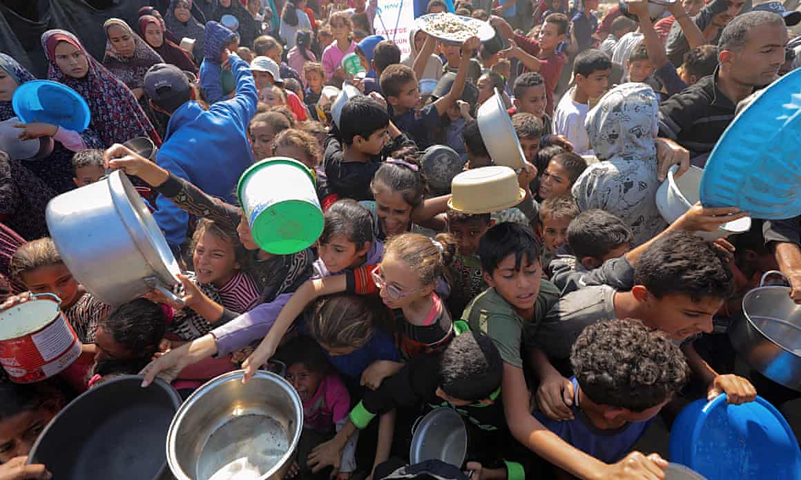A crowd of Palestinians, including many children, jostle for food