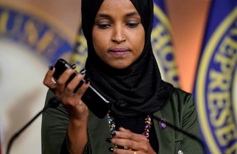 Ilhan Omar holds a phone, playing a voicemail message during a news conference