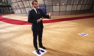 French President Emmanuel Macron makes a statement to the media as he stands on a physical distancing marker on arrival for an EU summit in Brussels, Sunday, July 19, 2020.