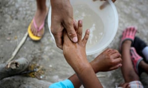 A Central American migrant washes the hands of a child at an encampment in Matamoros, Mexico, as more than 2,000 migrants seek asylum in the US.