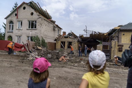Children watch as workers clean up after a rocket strike on a house in Kramatorsk, Donetsk region, eastern Ukraine, Friday, 12 August, 2022. There were no injuries reported in the strike.