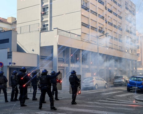 Fireworks explode near French riot police officers during a demonstration by French high school and university students in Lyon.