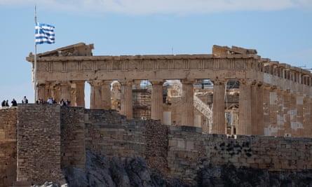 Greek flag flutters in front of the Parthenon Temple atop the Acropolis in Athens