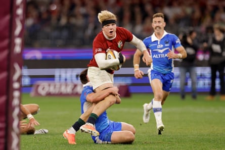 Henry Pollock holds on to the ball as he is tackled.