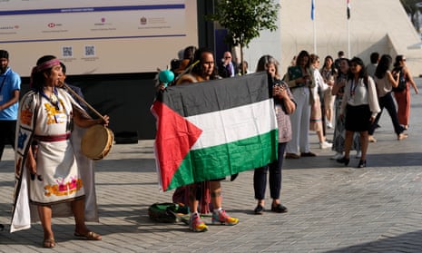 A man holds a Palestinian flag at the COP28 UN Climate Summit, Sunday, 3 December, in Dubai, United Arab Emirates. Moments later, authorities asked him to not hold the flag, per regulations on protests.