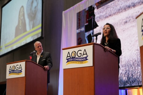 Man and woman stand on stage at lecterns marked AOGA