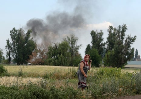 A woman speaks on a mobile phone on a roadside while smoke rises behind in the village Sviato-Pokrovske, Donetsk region yesterday.