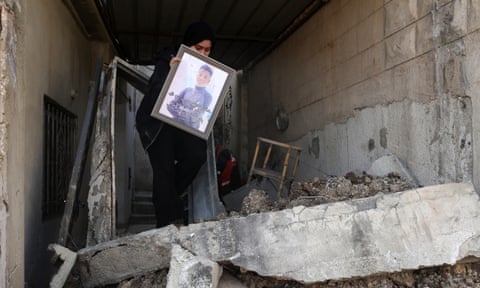 زنی یک عکس قاب شده را از خرابه های یک خانه نجات می دهد