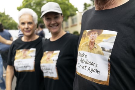 Three people wearing T-shirts with Donald Trump made to look like an Afrikaner farmer, above the slogan ‘Make Afrikaans Great Again’