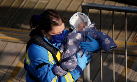 A coastguard officer with a baby that had been brought to Dover, Kent, on a Border Force vessel on 22 March 2022.