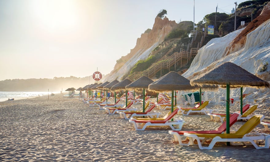 Colourful sun beds under straw umbrellas on Falesia Beach, Albufeira, Algarve, Portugal