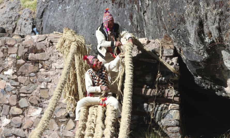 Los miembros de la comunidad Huinchiri utilizan técnicas tradicionales de tejido para reconstruir el puente colgante en Canas, Perú, el 13 de junio de 2021.