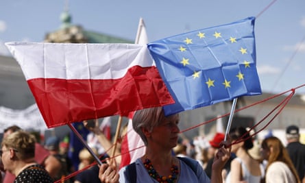 A woman holds the Polish and the European flag at the anti-government demonstration, in front of the presidential palace.