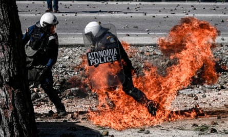 Greek riot police run away from a firebomb