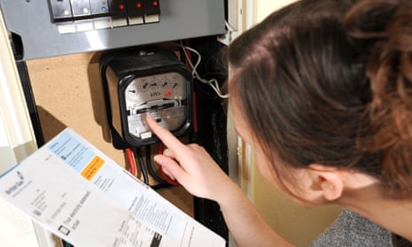 A woman reads her electricity meter while holding a bill