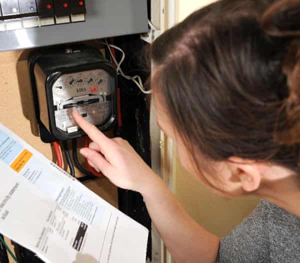 Young woman reads her electricity meter