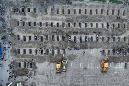 Aerial view of people digging dozens of graves