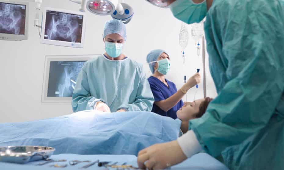 Surgeons and a nurse perform surgery