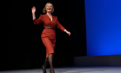 liz truss waving on stage in red suit