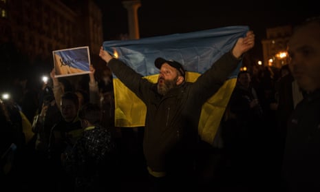 A man holds a Ukrainian flag behind him in central Kyiv as he celebrates the return of Kherson to Ukrainian control.