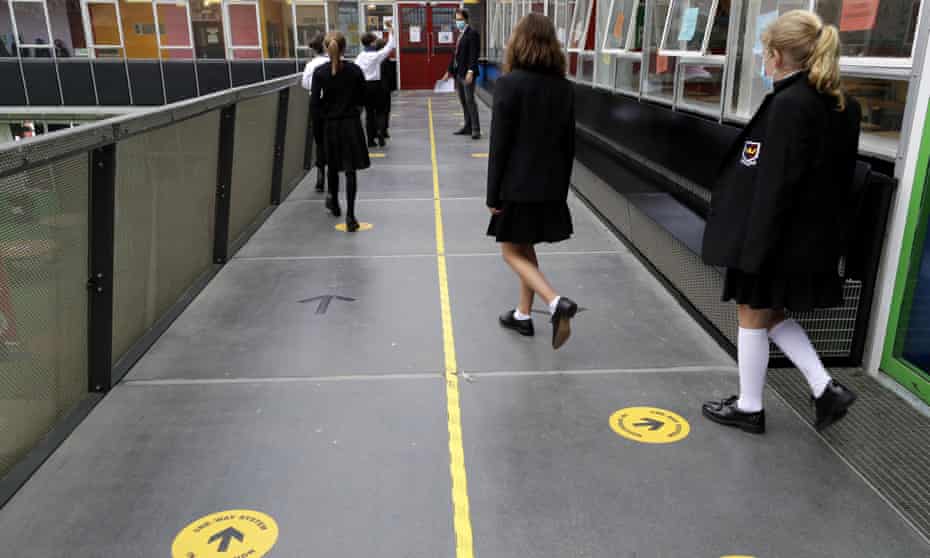 Pupils follow social distancing signs as they walk along a corridor at Kingsdale Foundation School in London