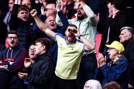 A Southampton fan sings as he watches the game through binoculars