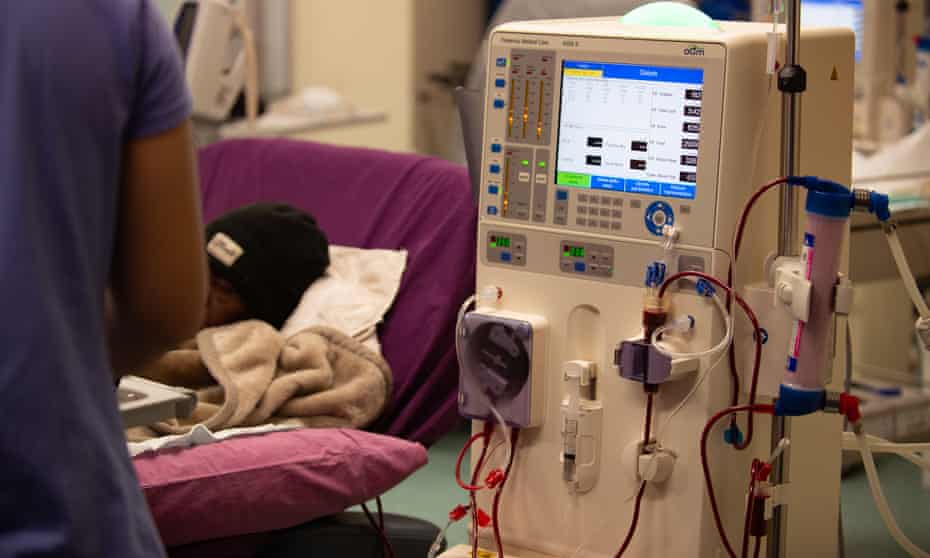 dialysis unit with a woman lying on a bed and a nurse standing by