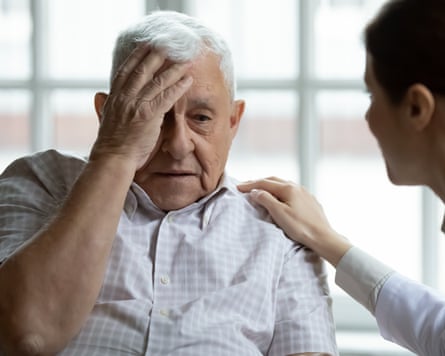 An older man looking unwell with a woman helping him.