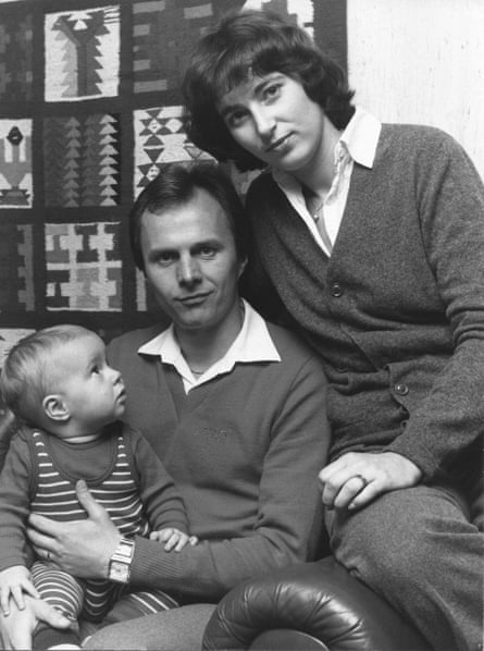 A black and white photograph of Sven-Göran Eriksson sitting in a chair holding a baby, with a woman sitting on the arm of the chair