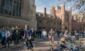 Cyclists and pedestrians move along Trinity Street past St Johns College, part of the University of Cambridge