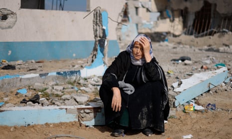 A woman rests next to a damaged building in Rafah after people were evacuated from Nasser hospital in Khan Younis.