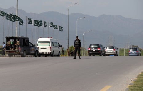 A Pakistani security official stands guard as vehicles carrying US officials pass after their arrival at Nur Khan air base.
