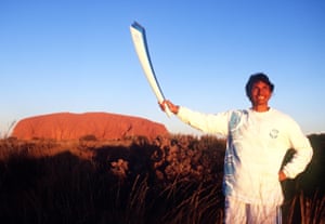 Nova Peris poses with the Olympic flame in front of Uluru, in Kata Tjuta national park, during the torch relay.