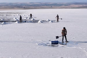 People digging with shovels on a large area of salt