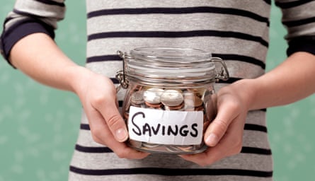 A child holds a jar full of coins with a label saying savings on it