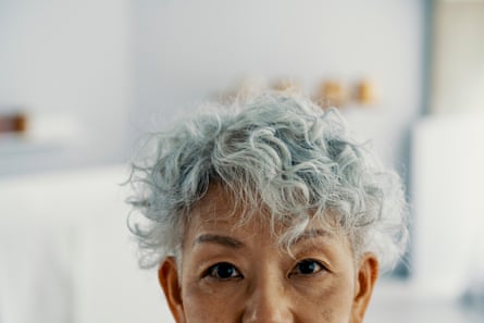 Close up of senior woman's face upper half with grey hair and wrinkles with a modern interior background