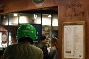 A Food delivery bike rider waiting to collect food from a restaurant.