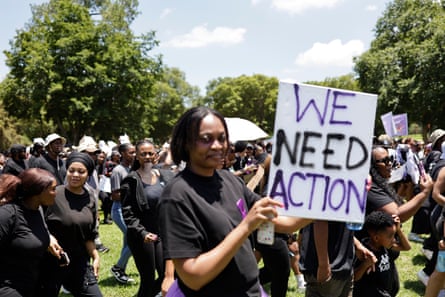 نساء أفريقيات يتجمعن في حديقة في بريتوريا للاحتجاج على العنف القائم على النوع الاجتماعي وقتل الإناث في جنوب إفريقيا. إحداهن تحمل لافتة كتب عليها: