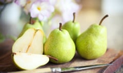 Green pears on wooden board with knife.
