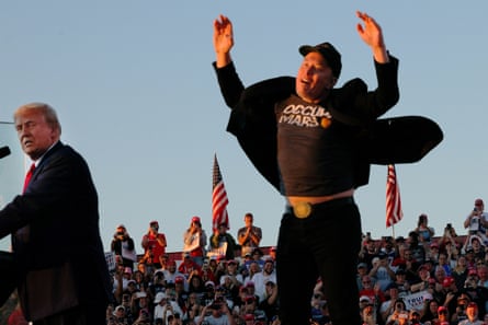 Man jumps up and down on stage as another man watches
