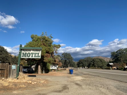 A sign stands outside Squaw Valley motel amid dry grass and gravel on the side of a two-lane road.