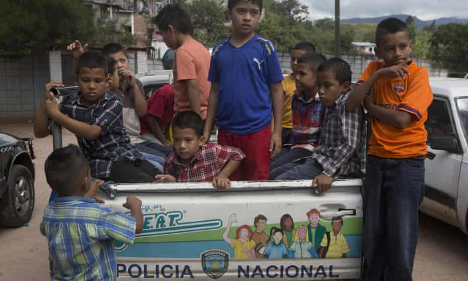 A group of Honduran children in Tegucigalpa climb into the back of a pick-up truck belonging to the National Police