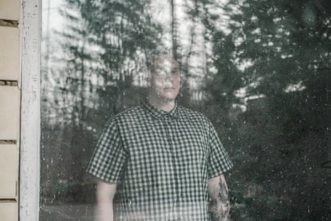 A man in a checked shirt looks out through a window