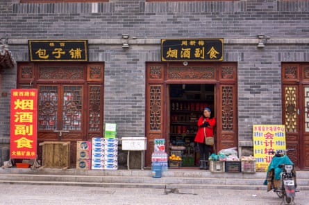 A woman looks outside from her grocery store.