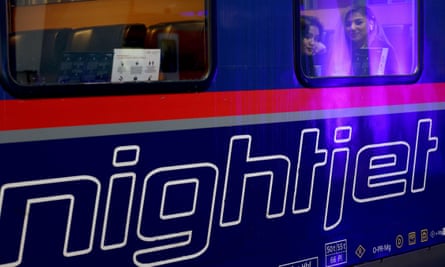 Passengers look outside the window of a Nightjet train at Vienna station.