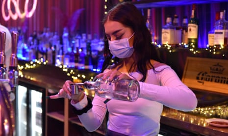 A bartender wearing a face mask pours a drink
